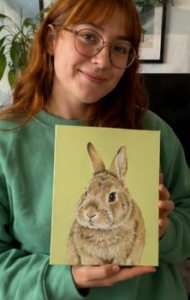 Chica joven con lentes con el cuadro de su mascota conejo